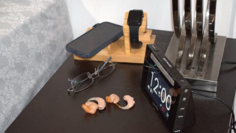DSC_0025 small black alarm clock on night table with hearing aids, glasses, cell and watch.
