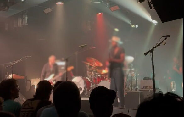 concert POV pic from audience with two guitar players and the backs of other audience members' heads