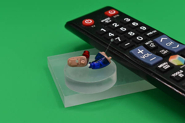 tv clicker with ITEs television remote beside 2 in the ear hearing aids
